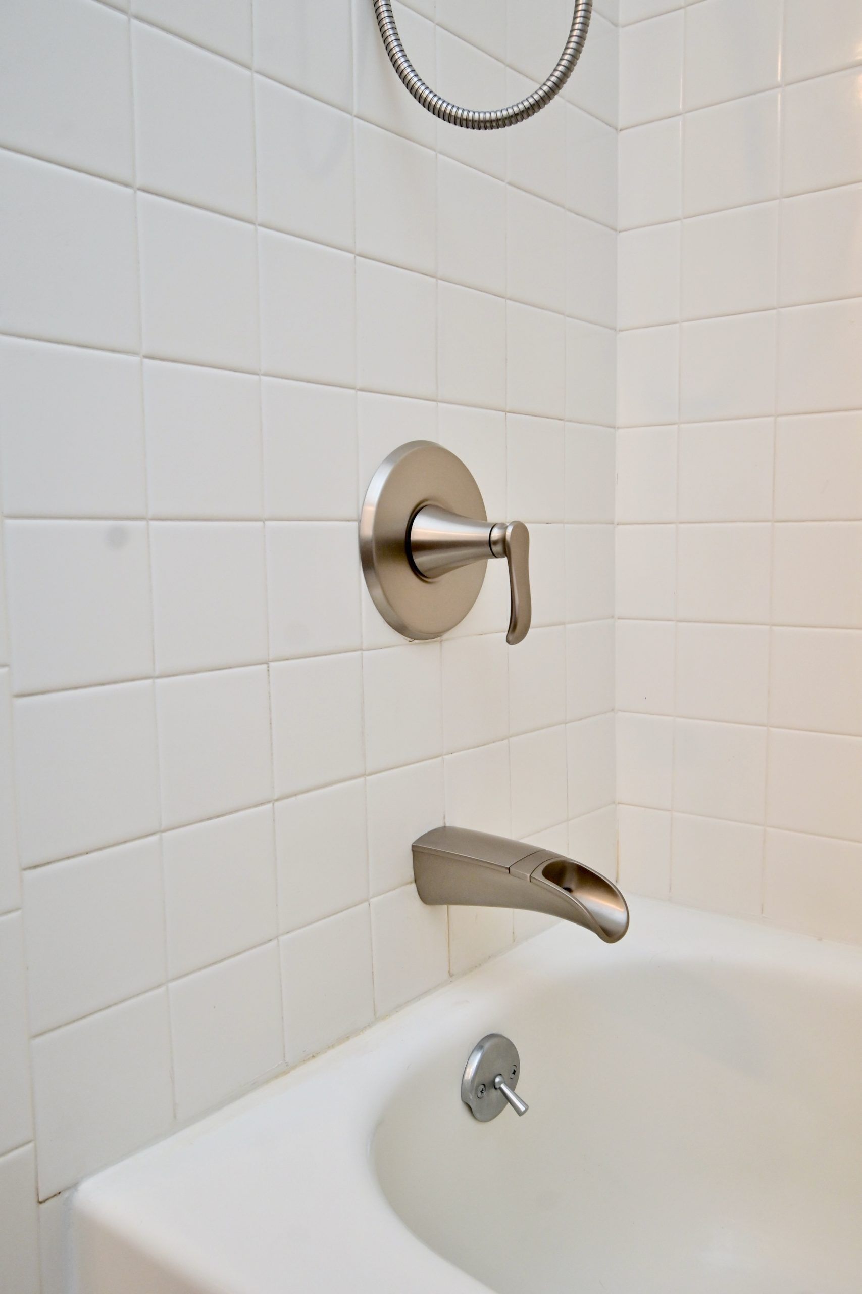 A bathtub in a bathroom with white tiles and a faucet