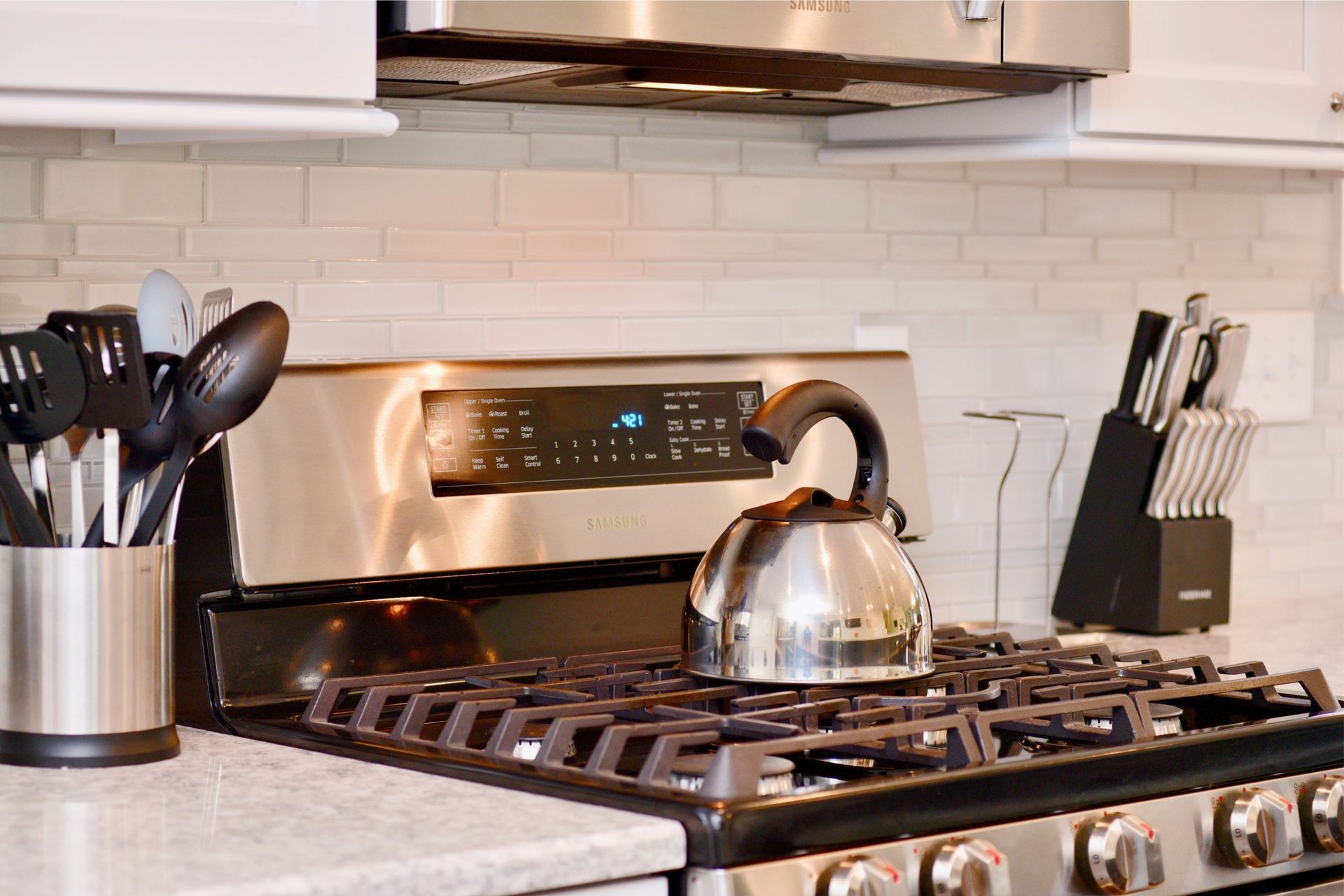 A stainless steel stove top oven with a tea kettle on top of it.