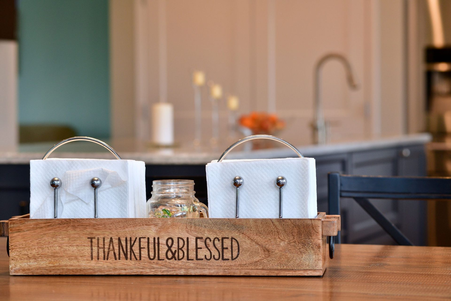 A wooden box with napkins in it is on a table in a kitchen.