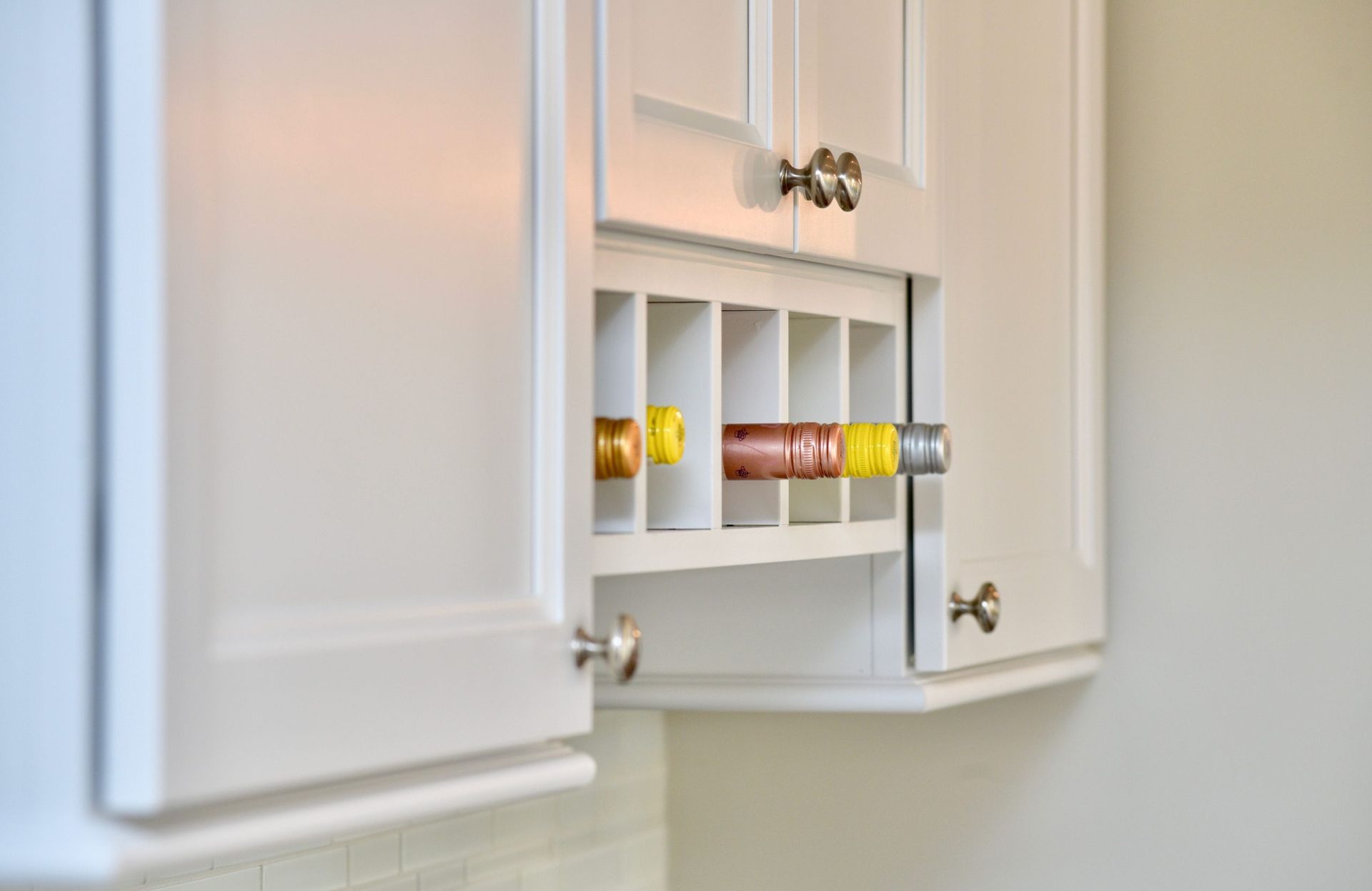A kitchen with white cabinets and a spice rack.
