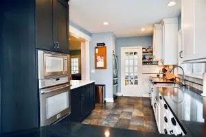 A kitchen with black cabinets , stainless steel appliances , a sink , and a microwave.