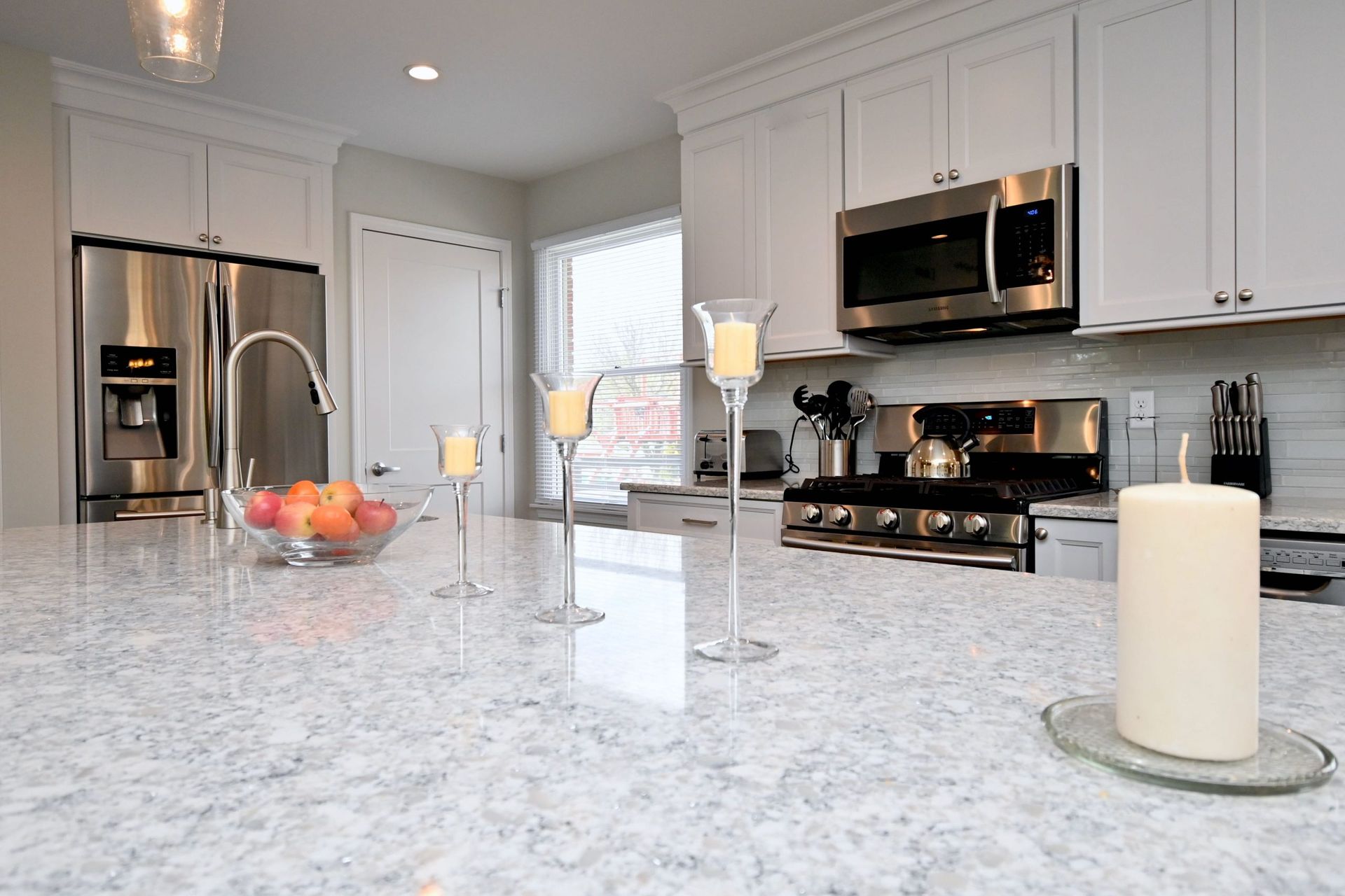 A kitchen with white cabinets and stainless steel appliances and a candle on the counter.