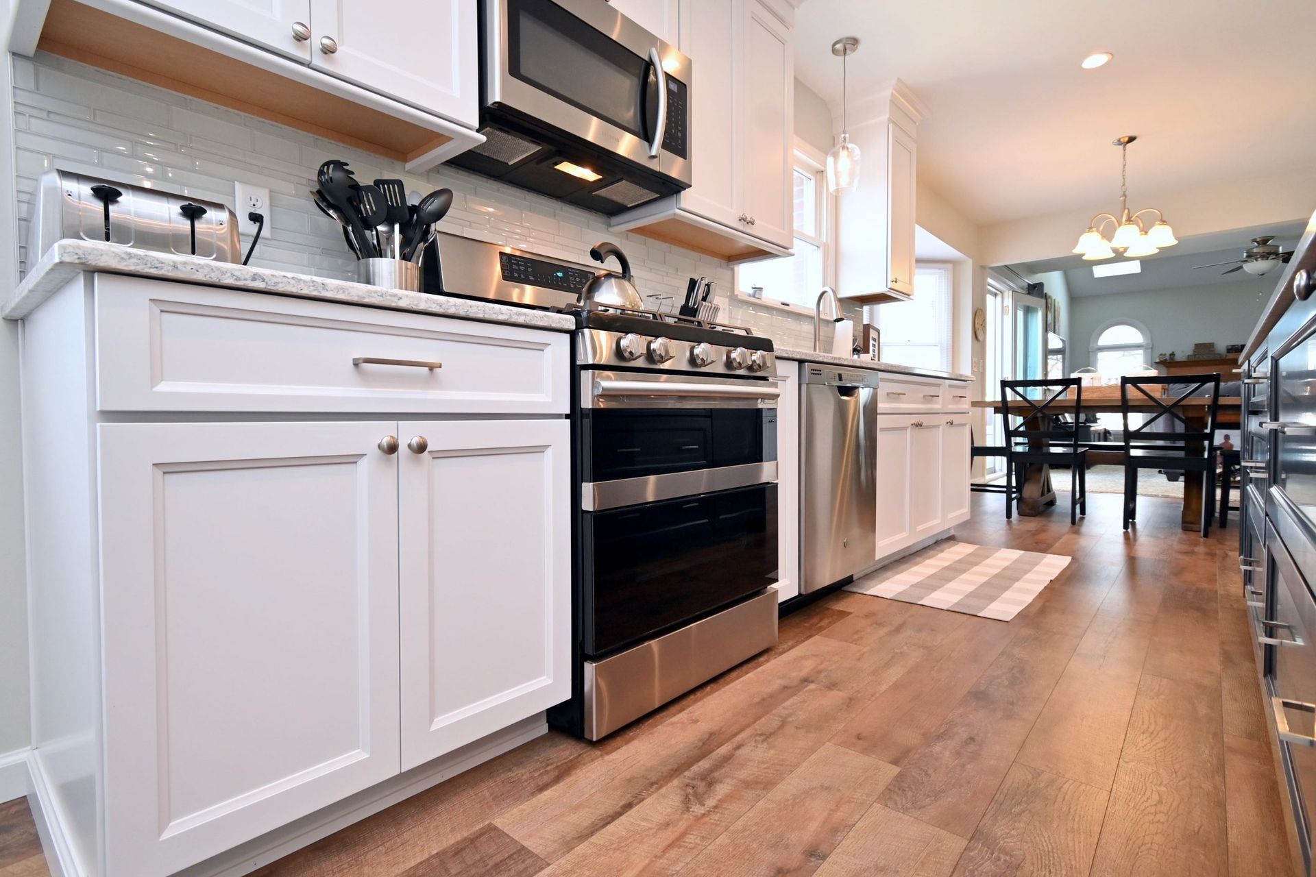 A kitchen with white cabinets , stainless steel appliances , and hardwood floors.