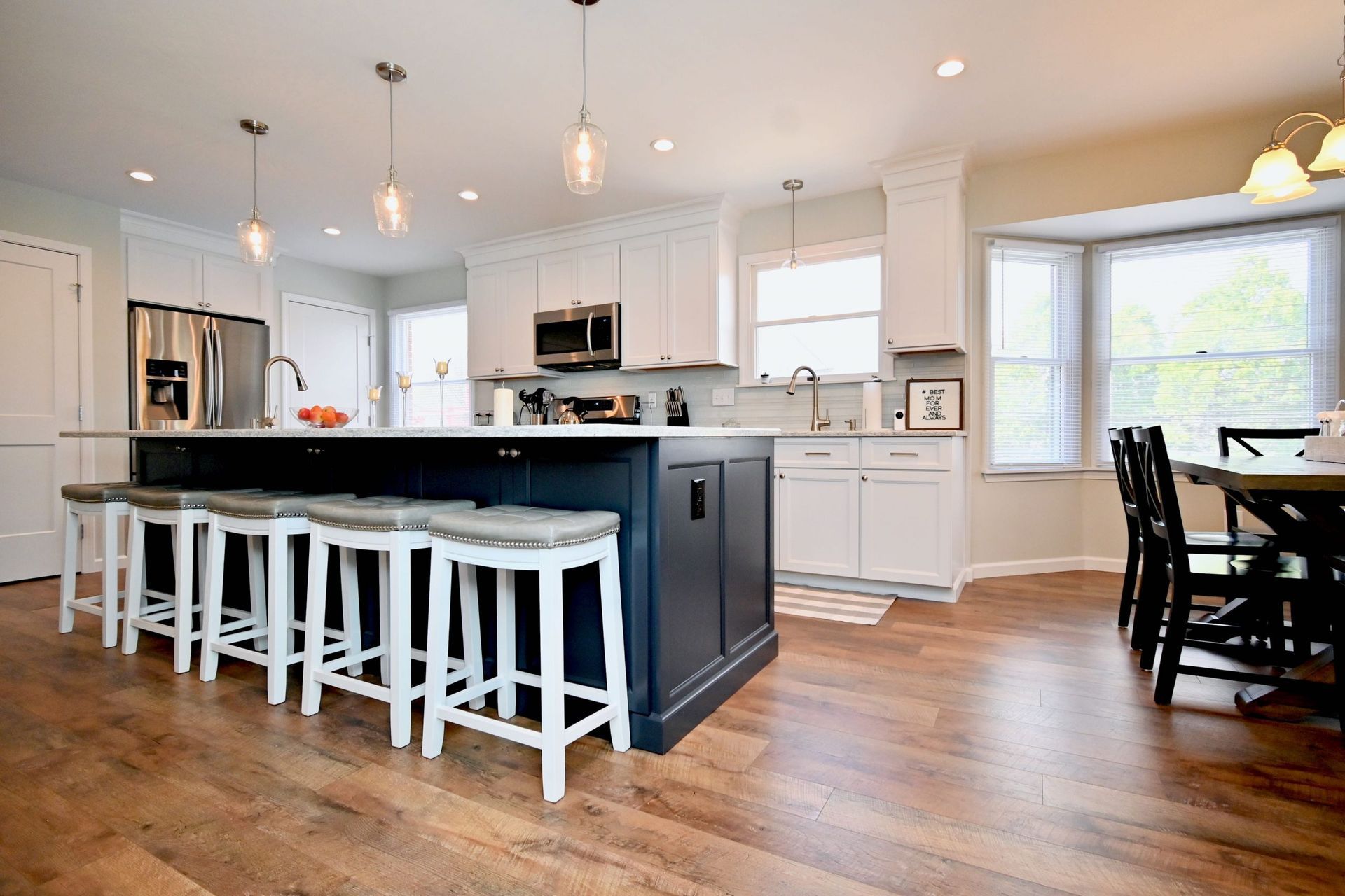 A kitchen with a large island , stools , a table and chairs.