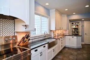 A kitchen with white cabinets , stainless steel appliances , a sink and a window.