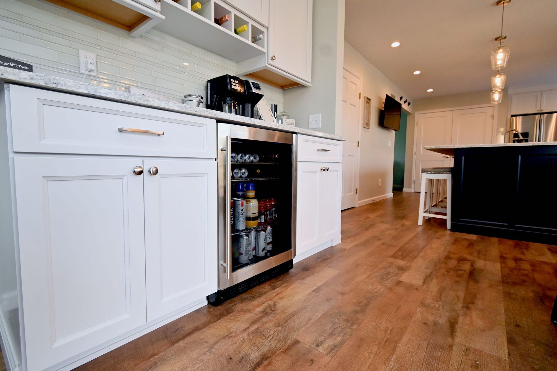 A kitchen with white cabinets and a stainless steel refrigerator.