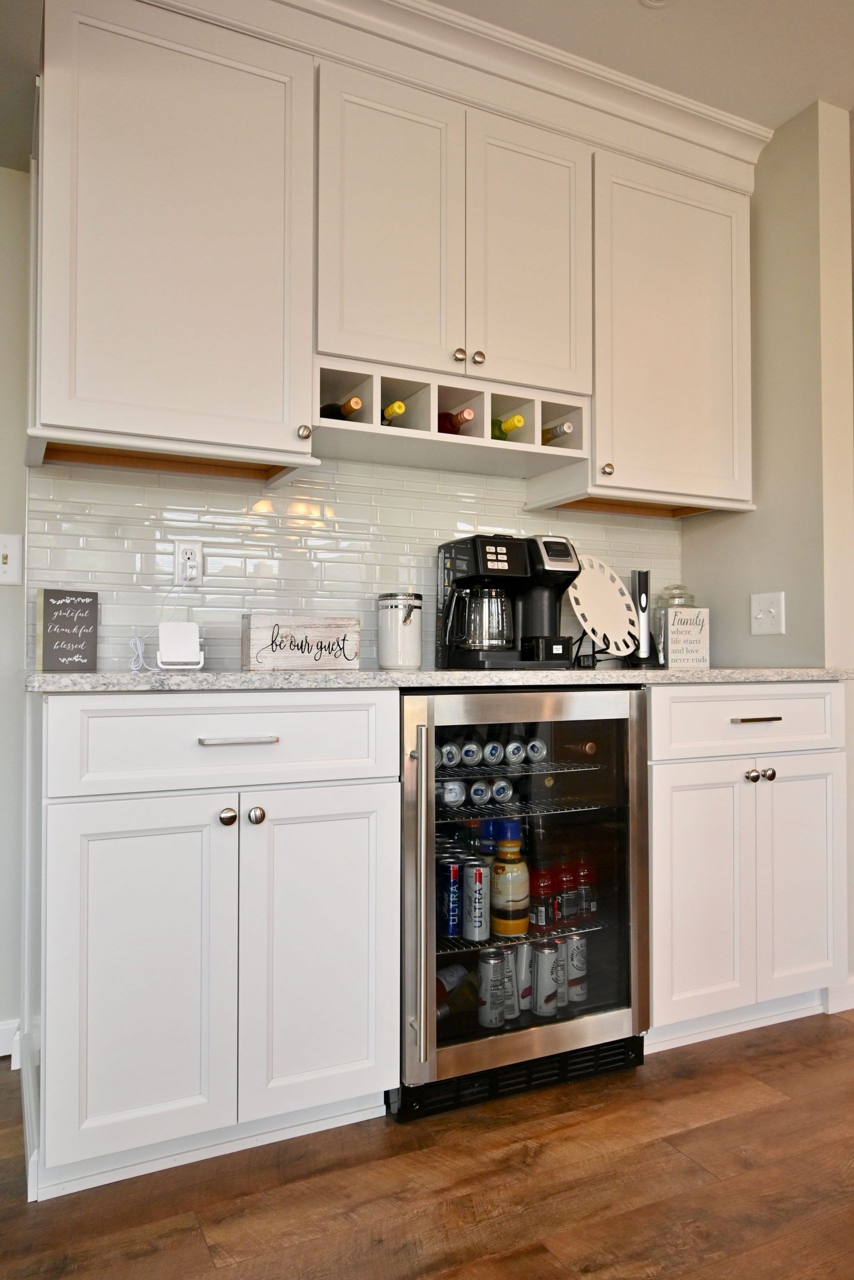 A kitchen with white cabinets and a stainless steel refrigerator.