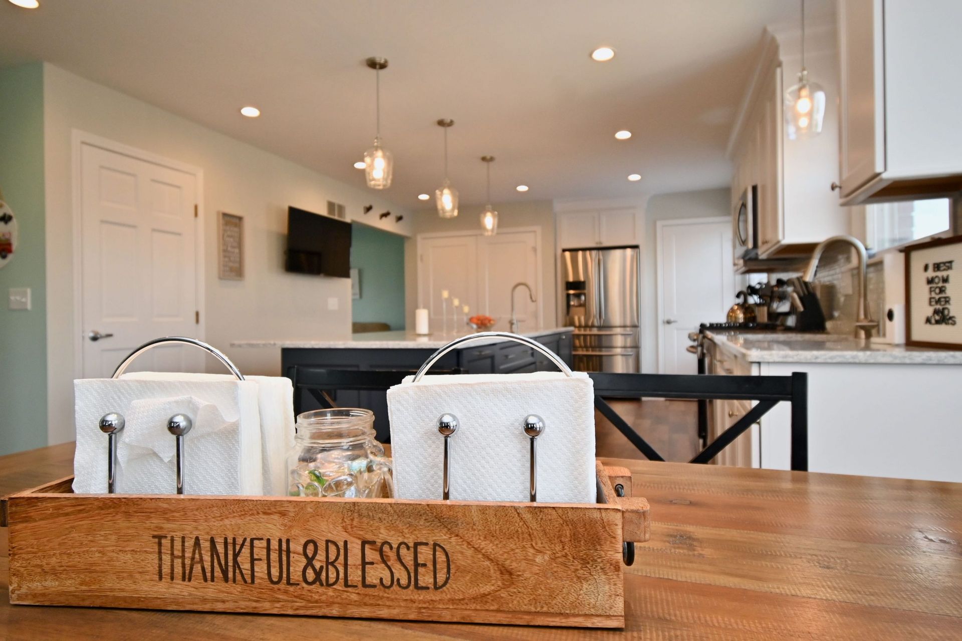 A wooden box that says `` thankful & blessed '' is on a wooden table in a kitchen.
