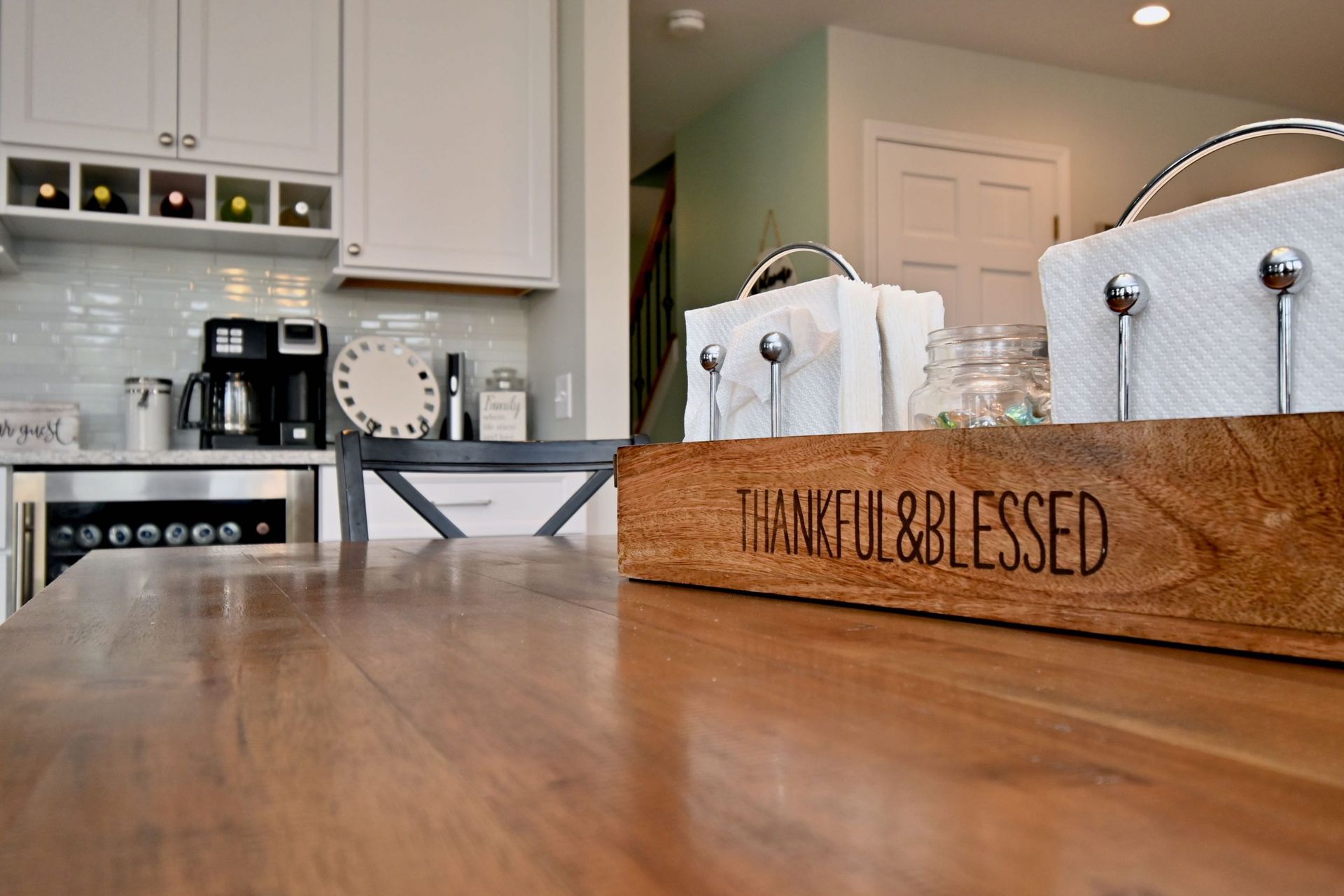 A wooden box that says thankful and blessed is on a wooden table in a kitchen.