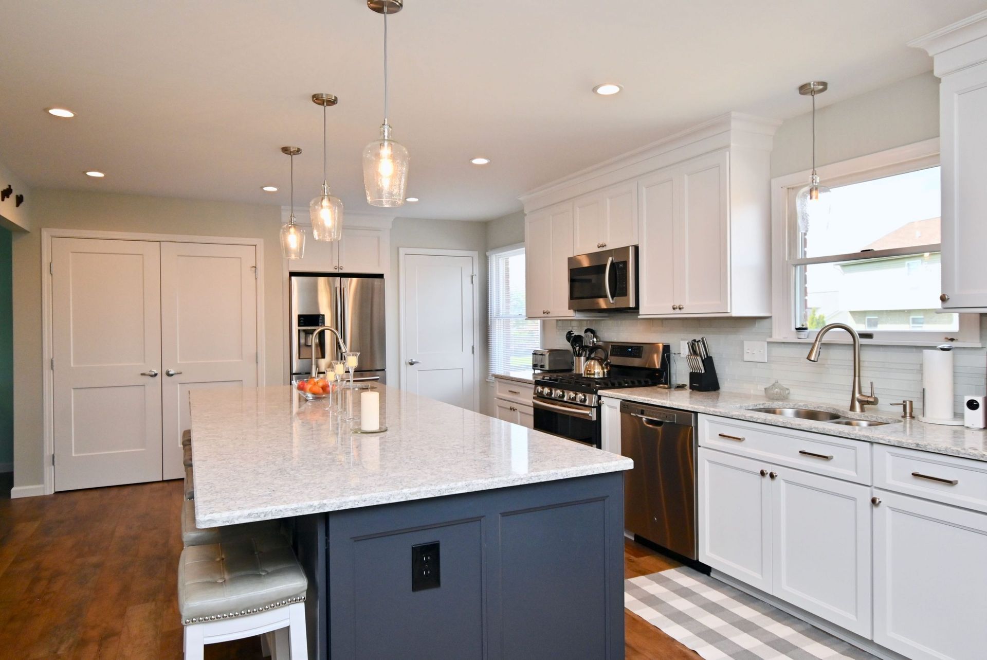 A kitchen with white cabinets , stainless steel appliances , and a large island.