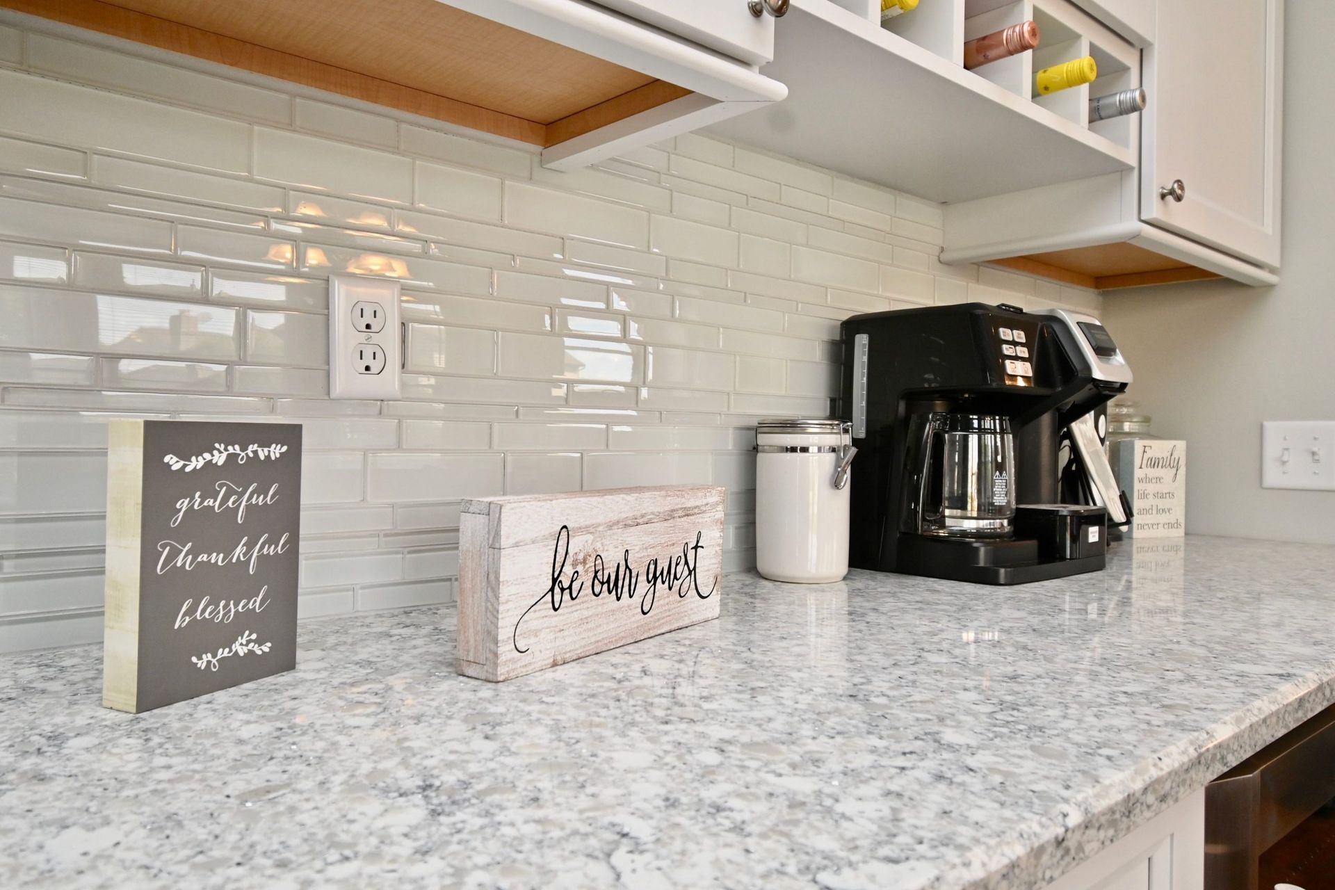 A kitchen counter with a coffee maker and a sign on it.