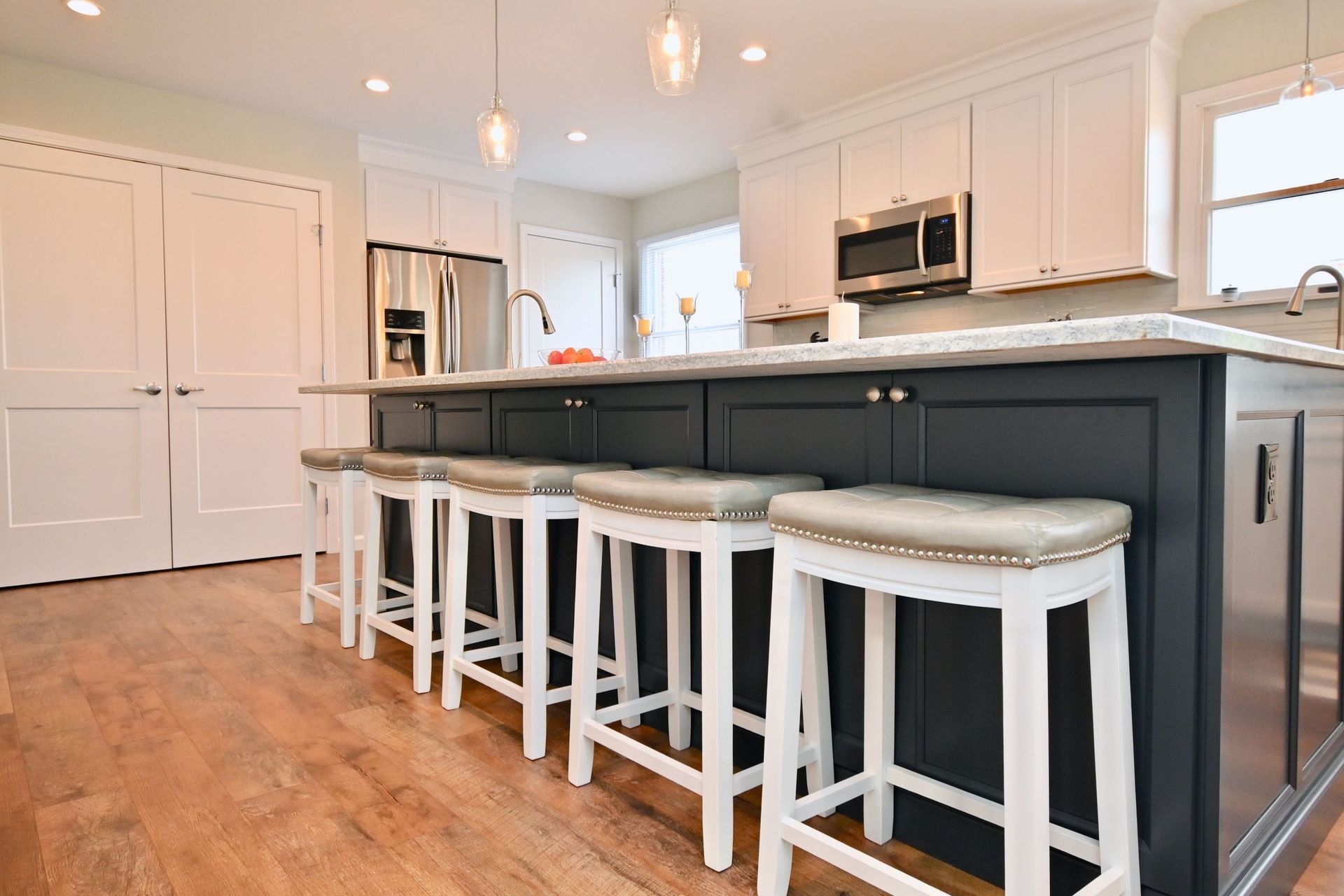 A kitchen with a large island and white stools.