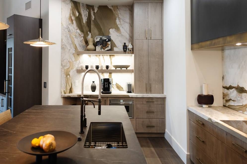A kitchen with a sink and a bowl of fruit on the counter.