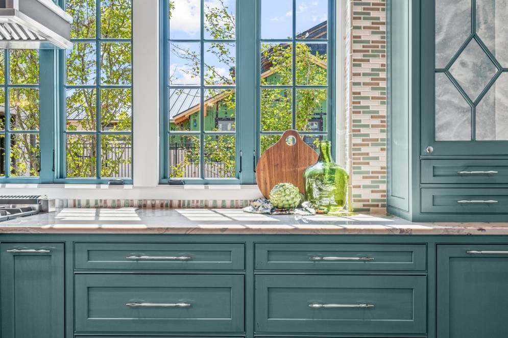 A kitchen with green cabinets and a stove top oven.
