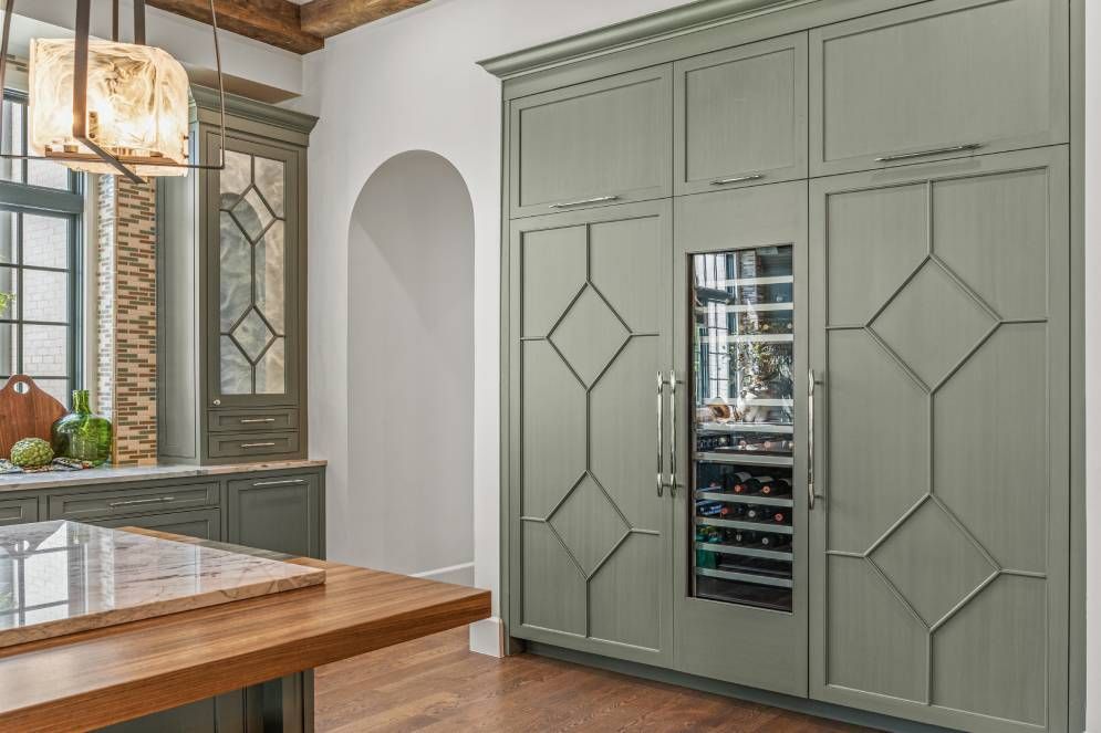 A kitchen with green cabinets and a wine cooler.