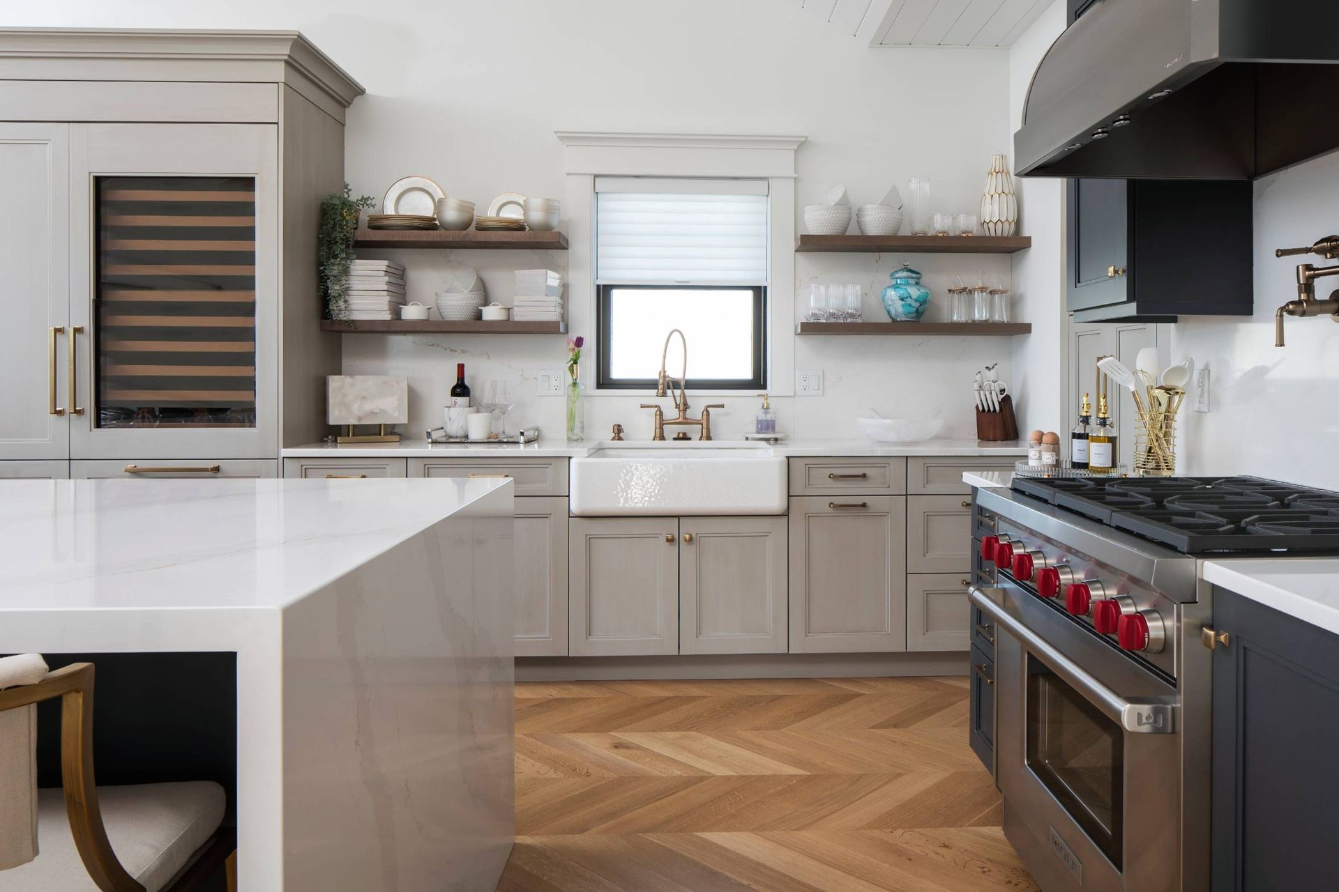 A kitchen with stainless steel appliances , gray cabinets , a sink , and a stove.