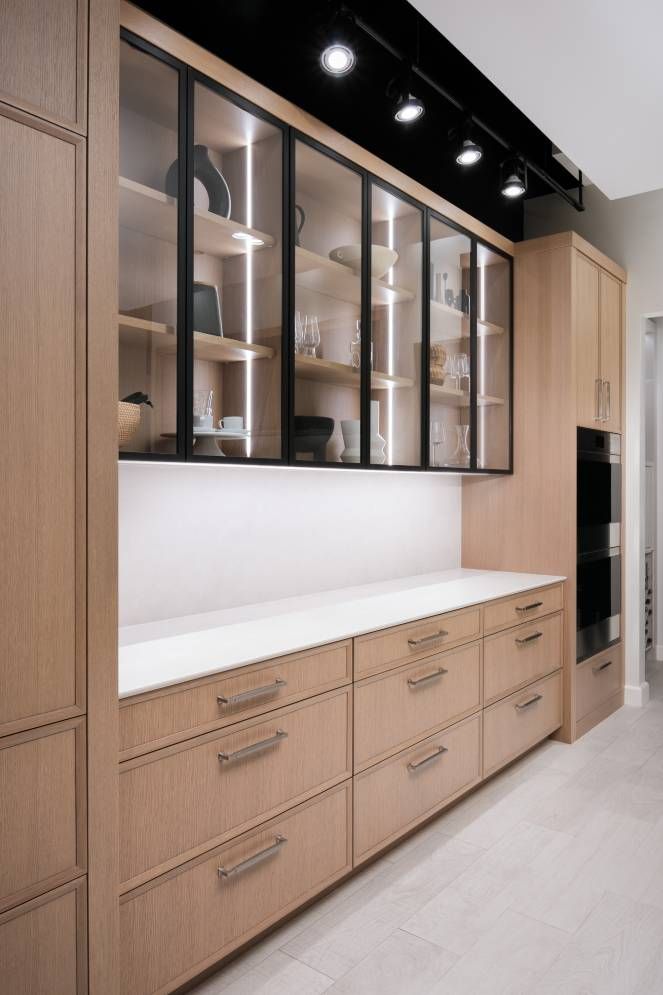 A kitchen with wooden cabinets and drawers and glass doors.