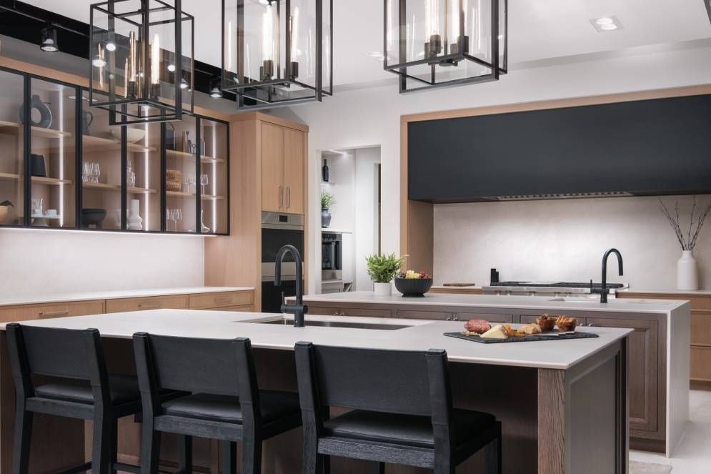 A kitchen with a large island and chairs and a chandelier hanging from the ceiling.