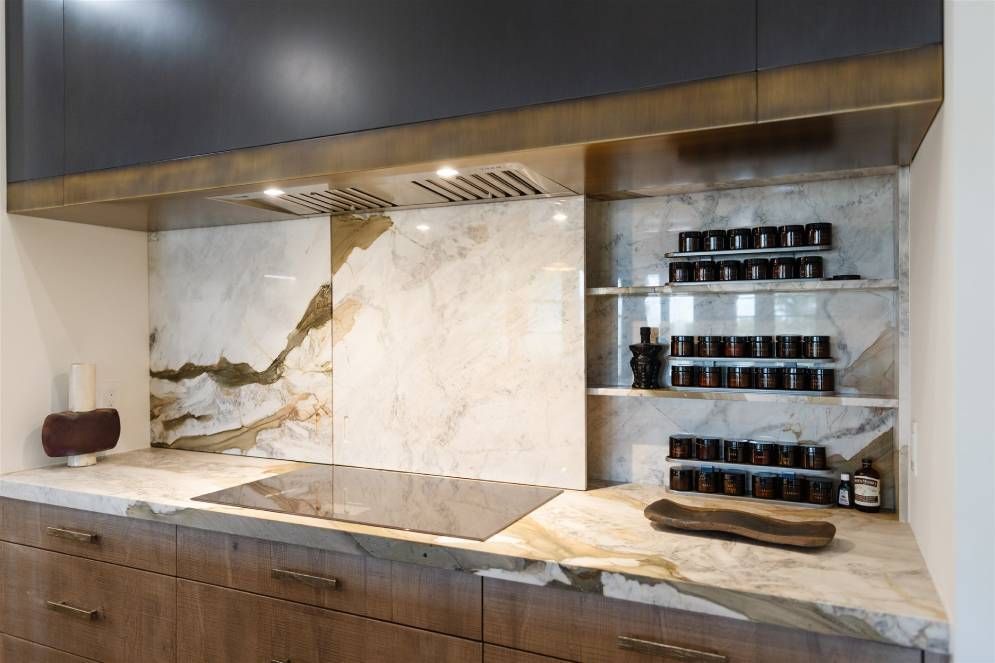 A kitchen with a stove top oven and marble counter tops.