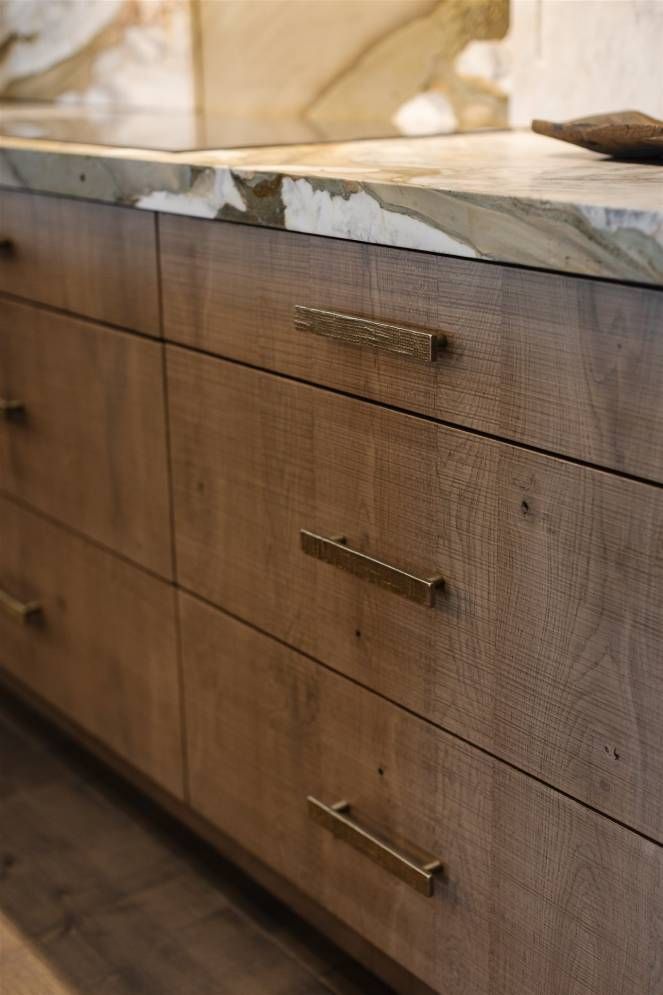 A close up of a wooden dresser with drawers and a marble counter top.
