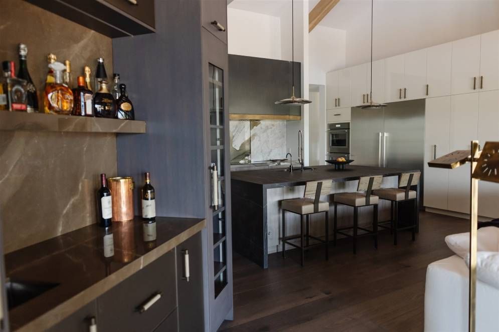 A kitchen with a bar and bottles on the counter