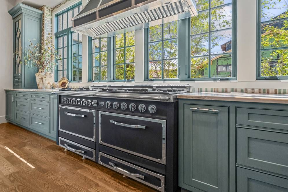 A kitchen with a large stove and lots of windows.