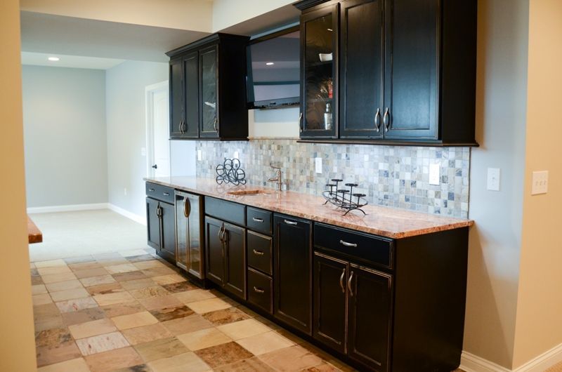 A kitchen with black cabinets and granite counter tops.