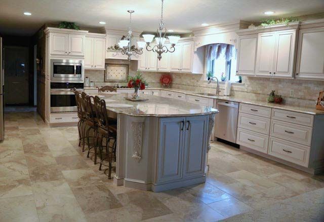 A kitchen with white cabinets , granite counter tops , stainless steel appliances and a large island.