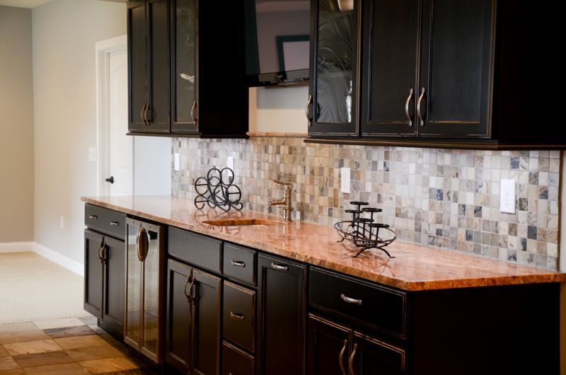 A kitchen with black cabinets and granite counter tops.