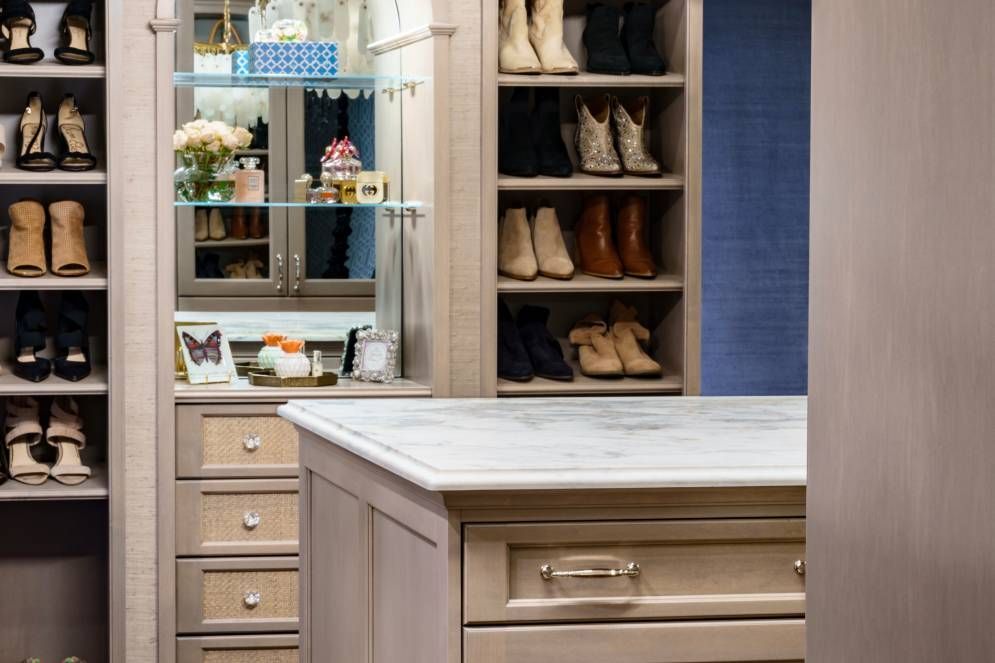 A walk in closet with lots of shoes on shelves
