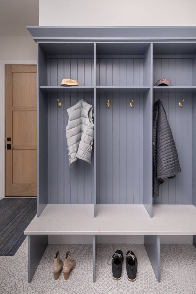 A mud room with a bench and clothes hanging on the wall.