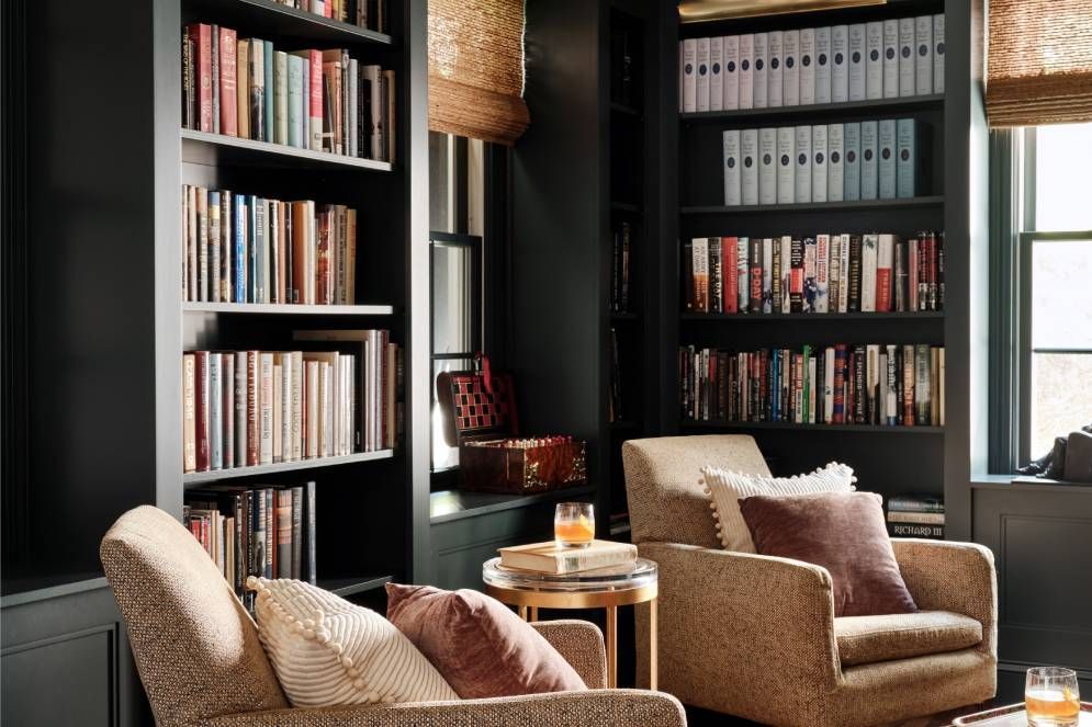 A living room with two chairs and a bookshelf filled with books.