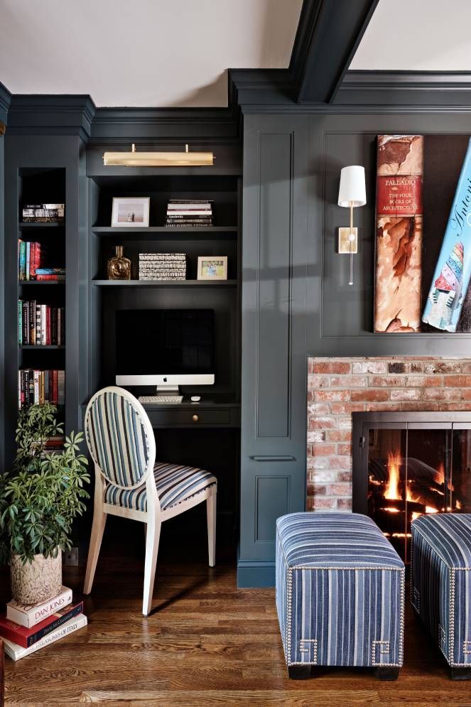 A living room with a fireplace and a desk with a computer on it.