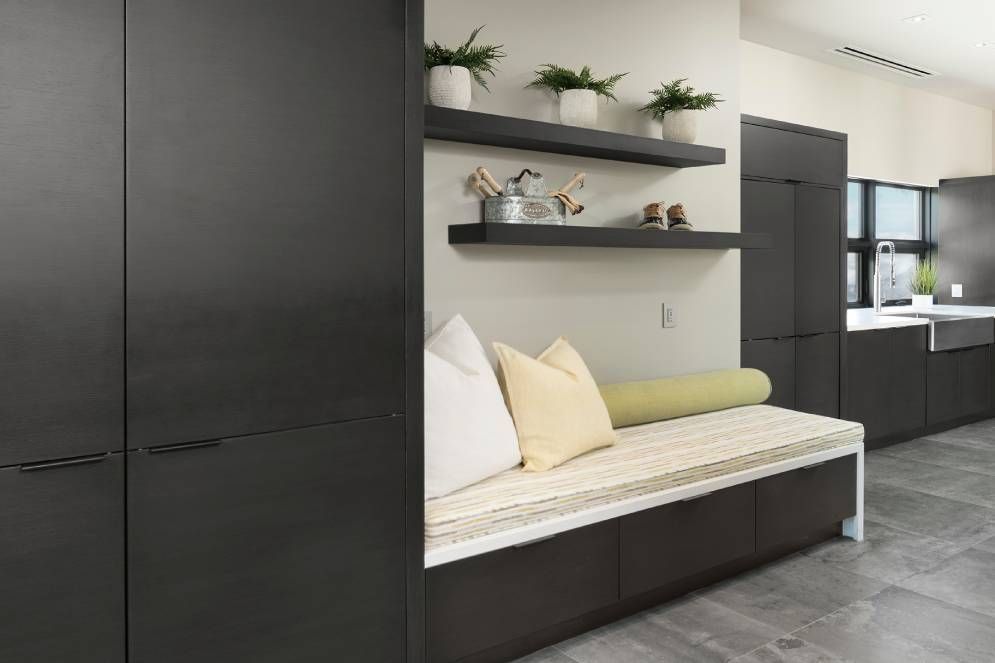 A kitchen with black cabinets and a bench with pillows on it.