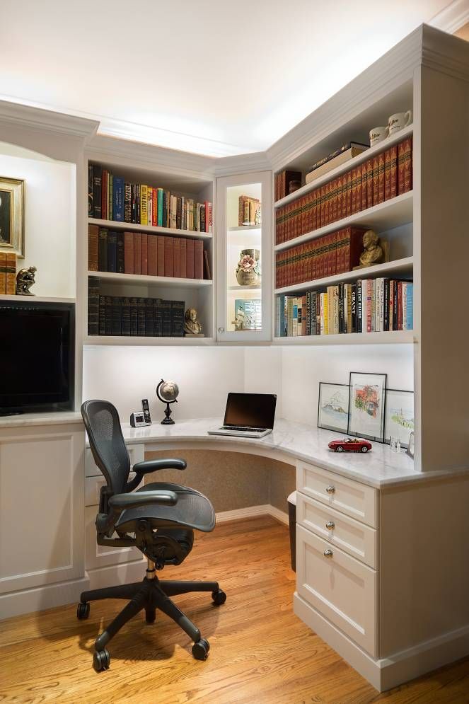 A home office with a desk , chair , and shelves filled with books.