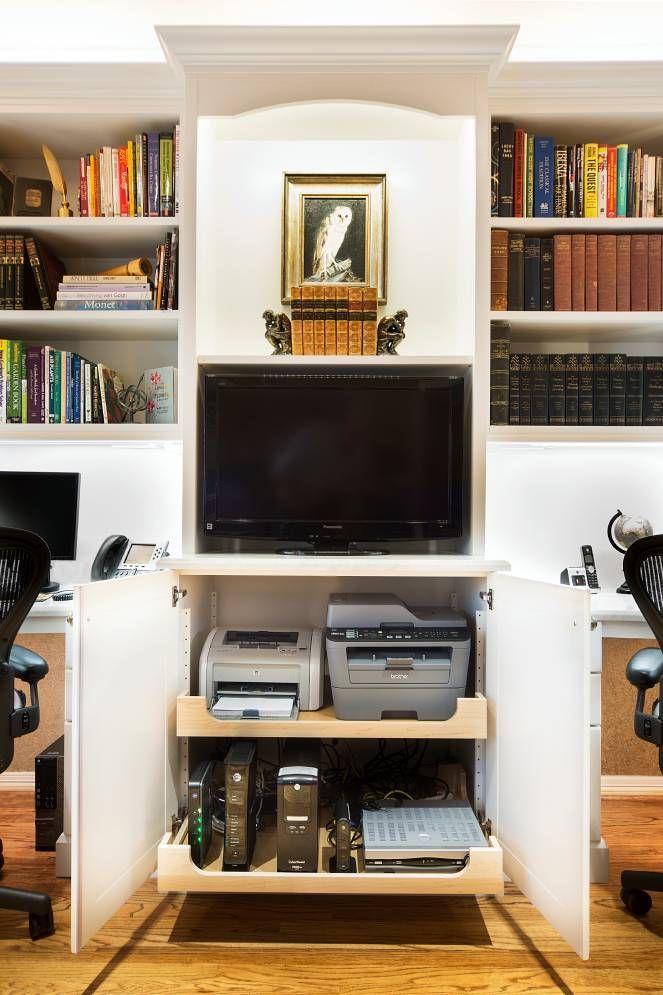 A home office with two desks , a printer , and a television.