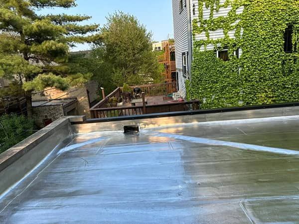 Outdoor rooftop water feature with a reflective pool, trees, and an ivy-covered building in the background