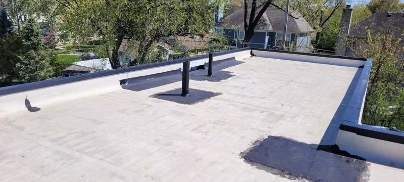 Flat rooftop with vents, a low parapet, and trees visible in the background.
