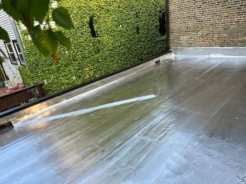 Shiny concrete patio beside a brick wall and green ivy-covered fence