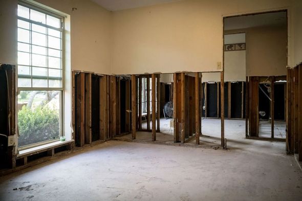 Empty room undergoing renovation with exposed wooden framing and large window.
