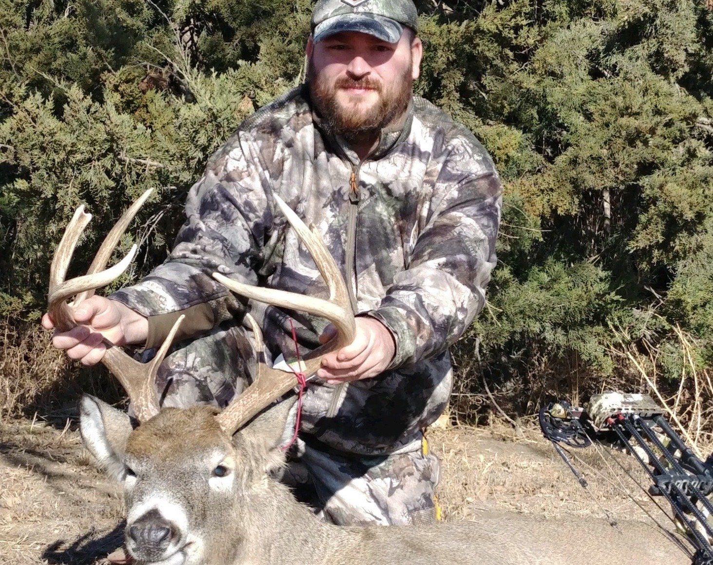 A man is kneeling down next to a deer.