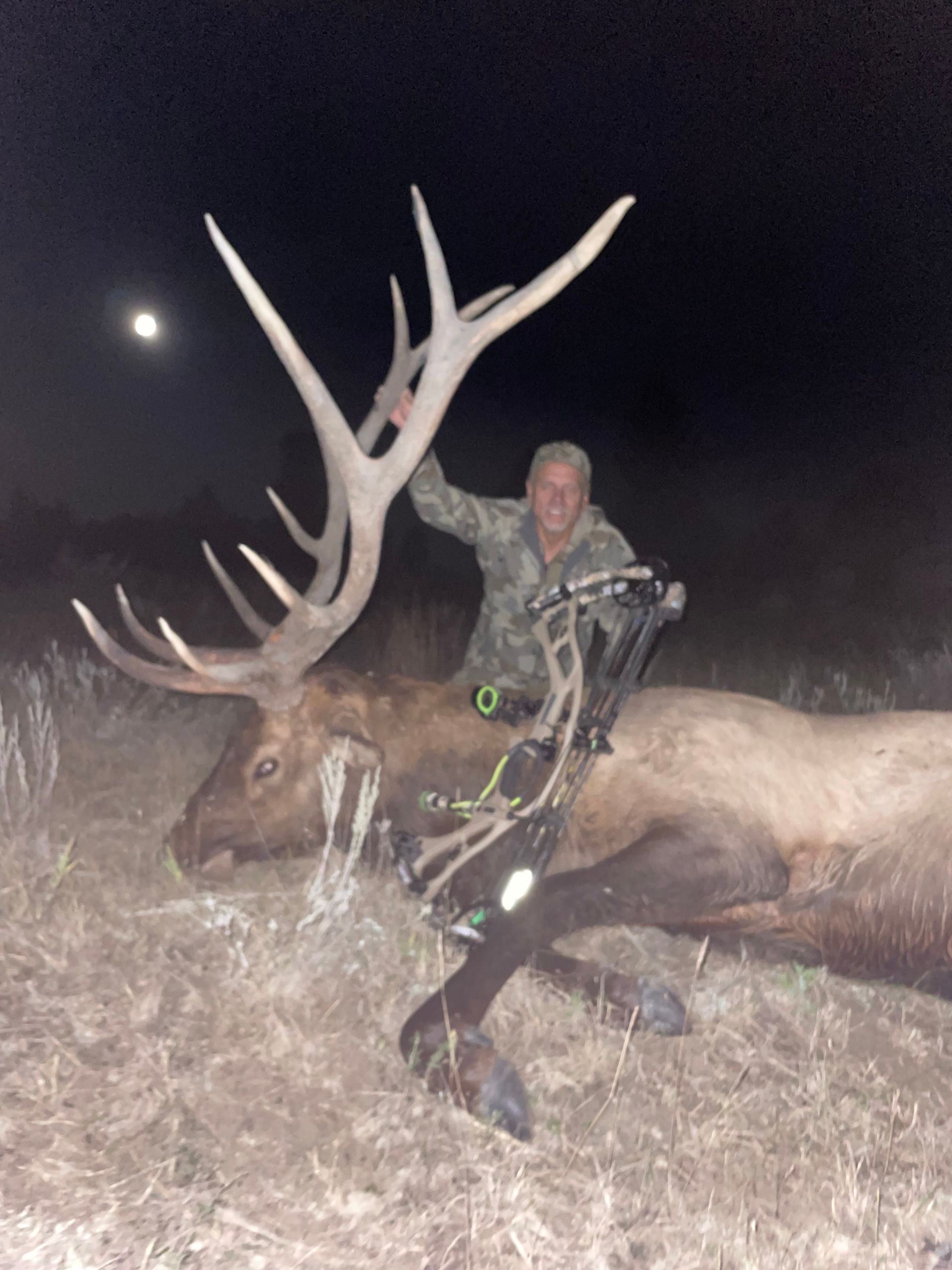 man holding a dead deer at night