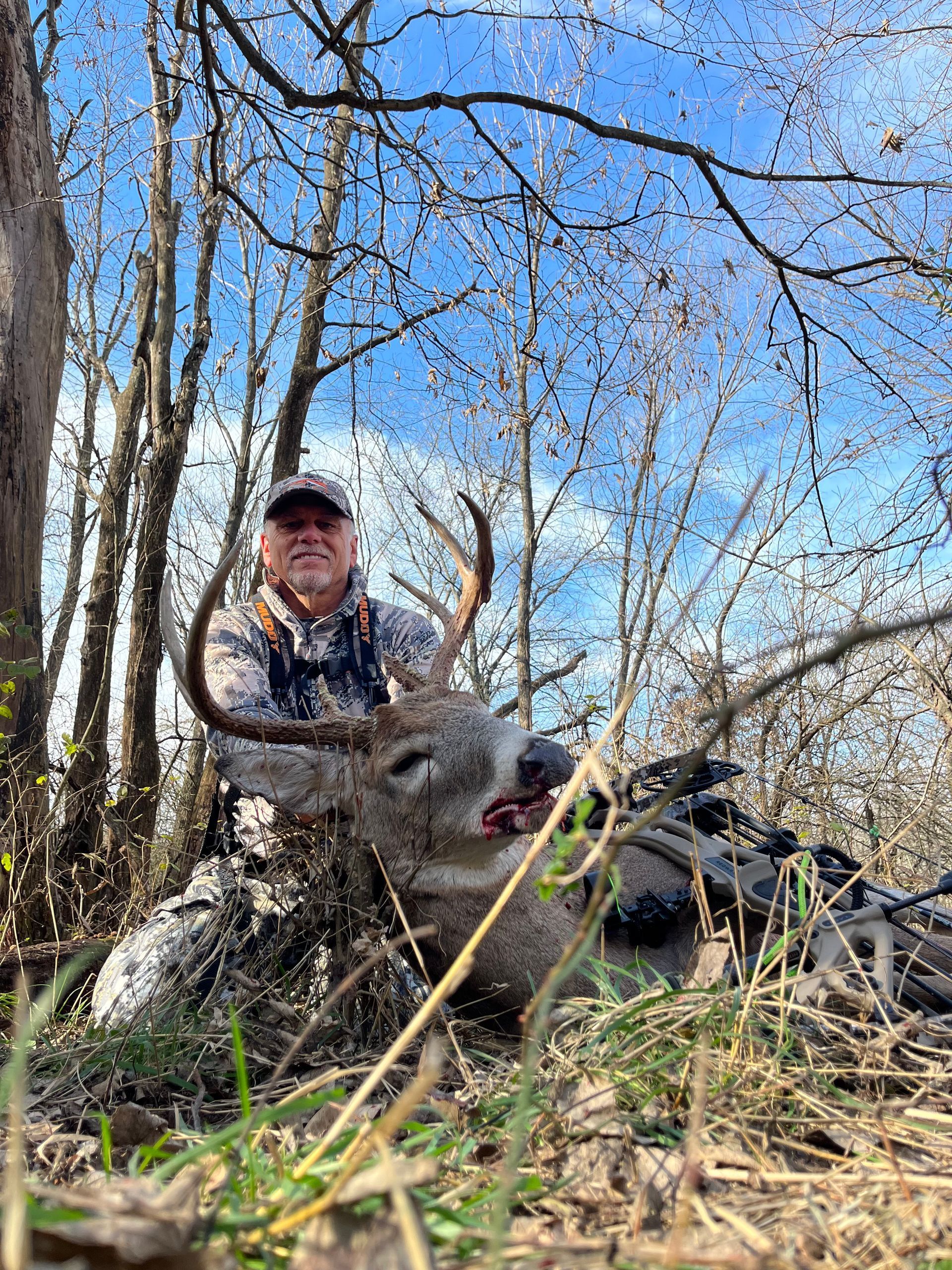 man holding a dead deer in the forest