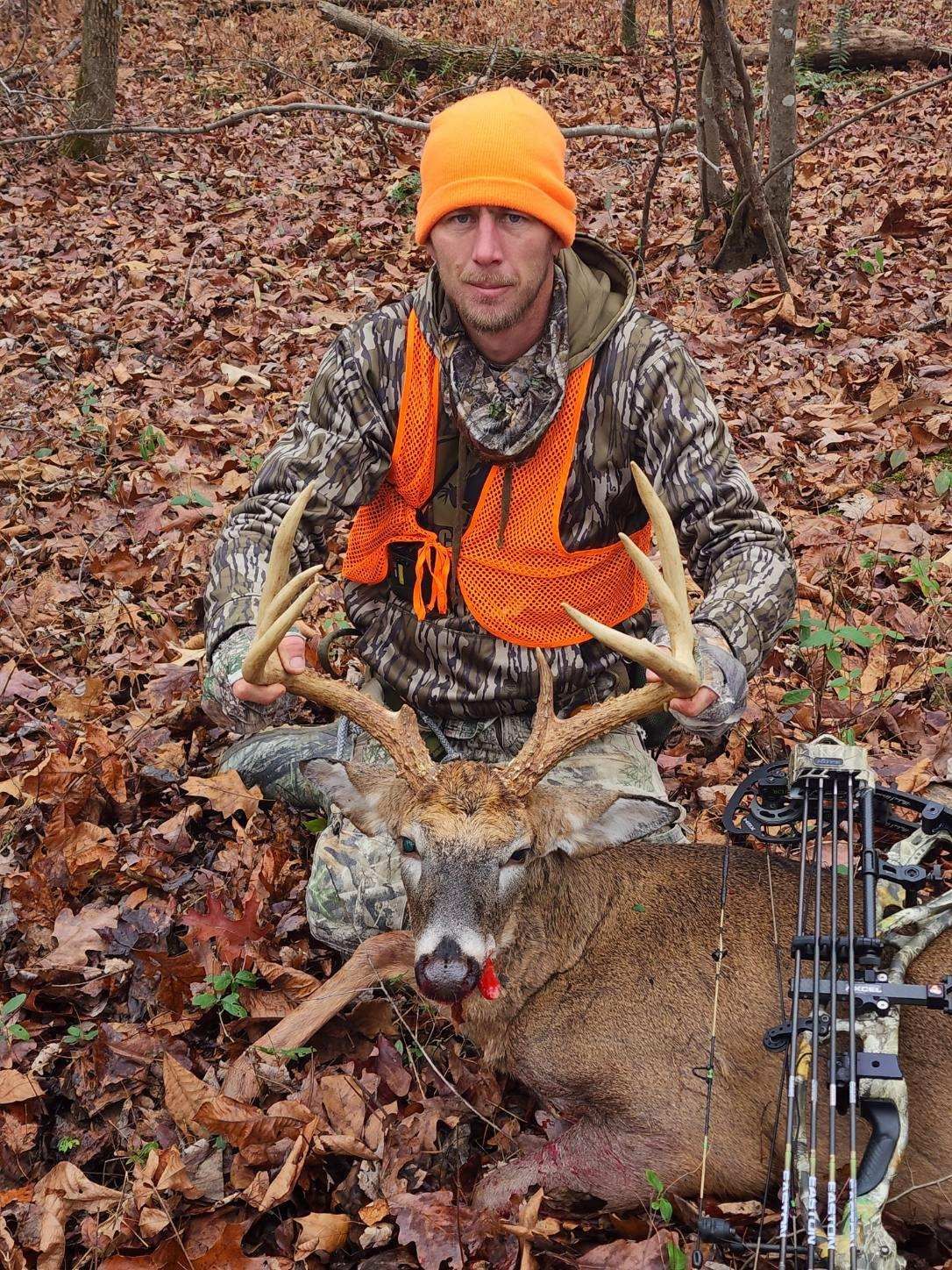 man with an orange beanie with a dead deer