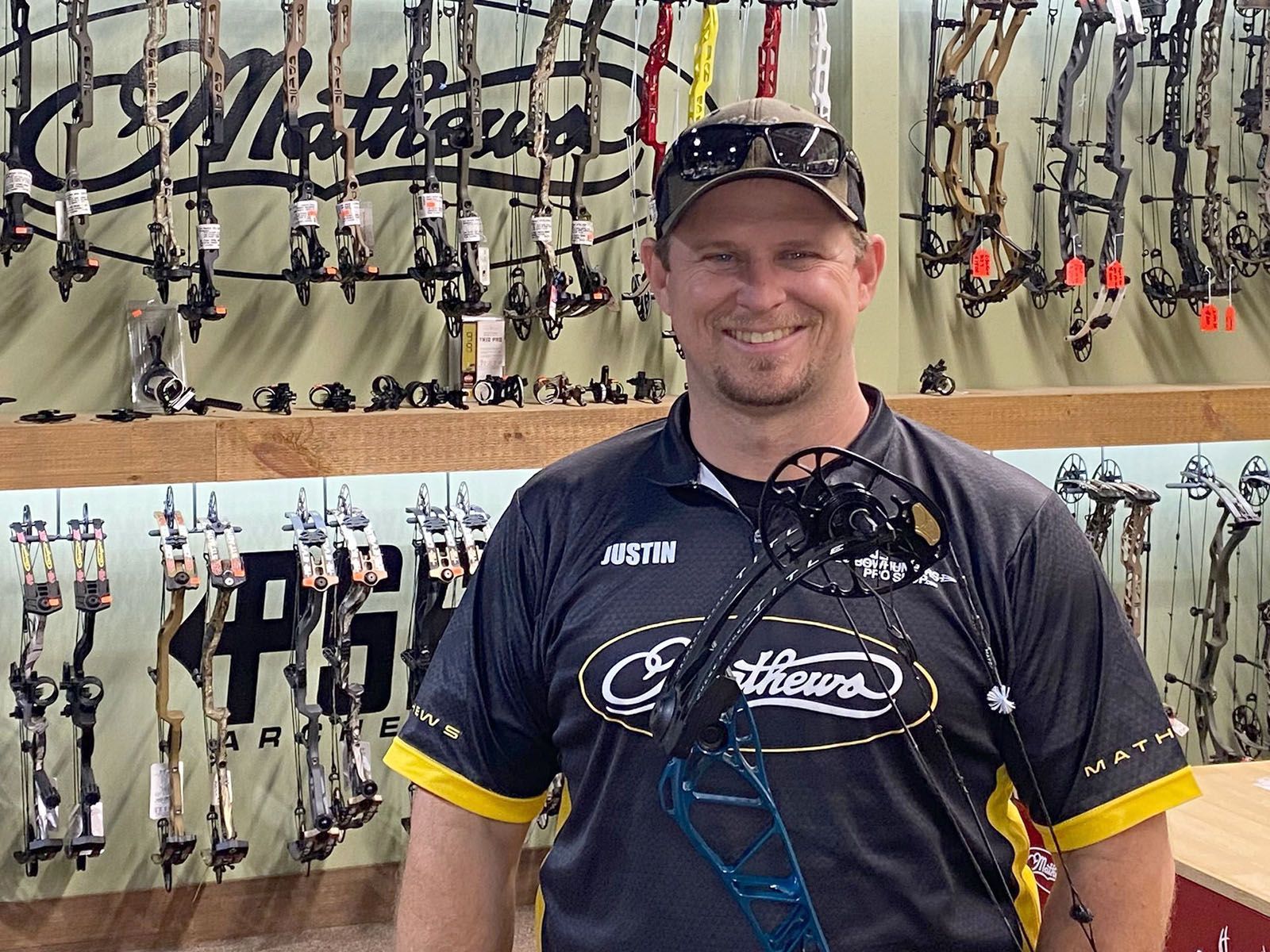A man in a black archery shirt holding a bow