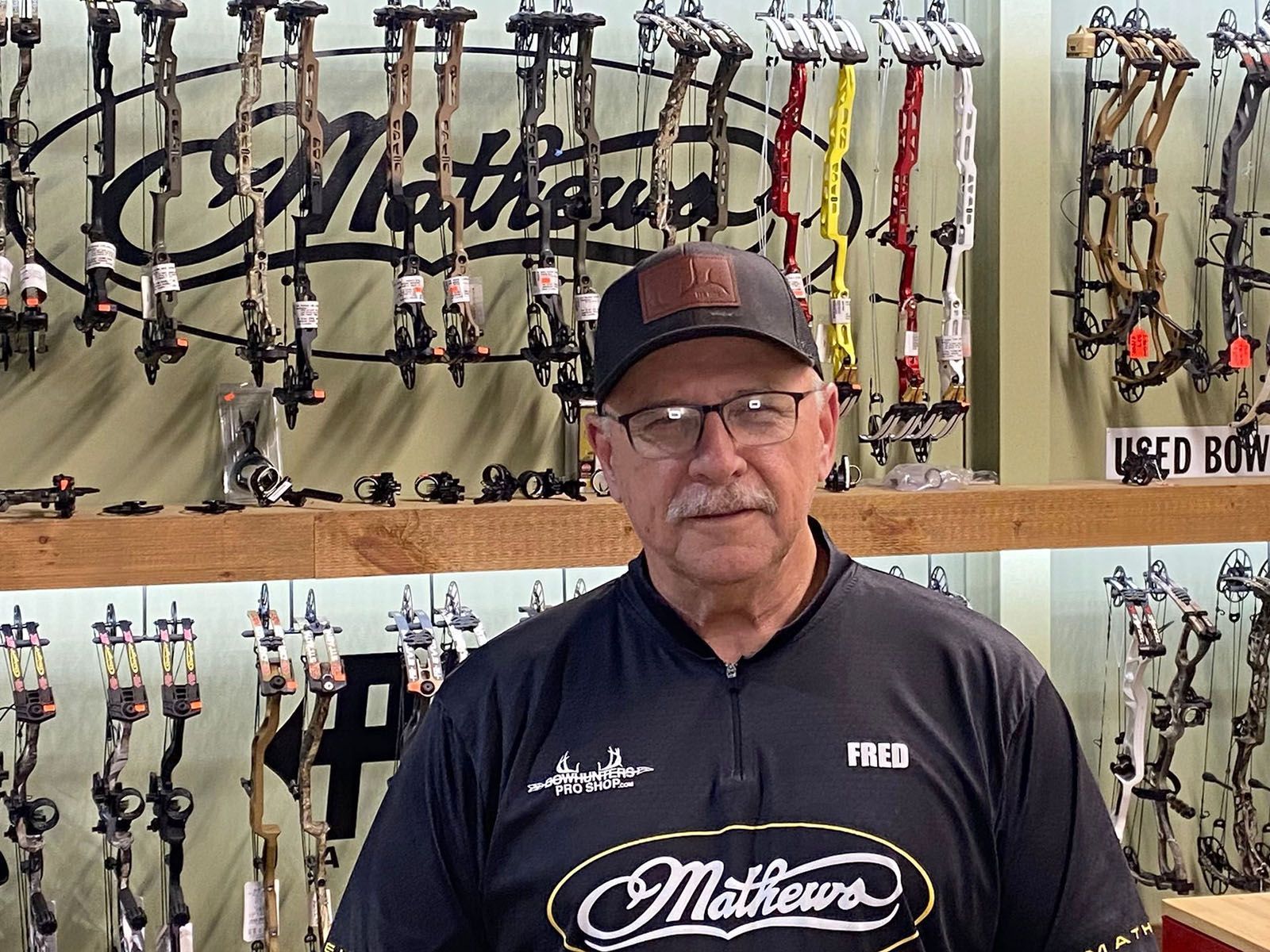 A man in a black archery shirt with black cap