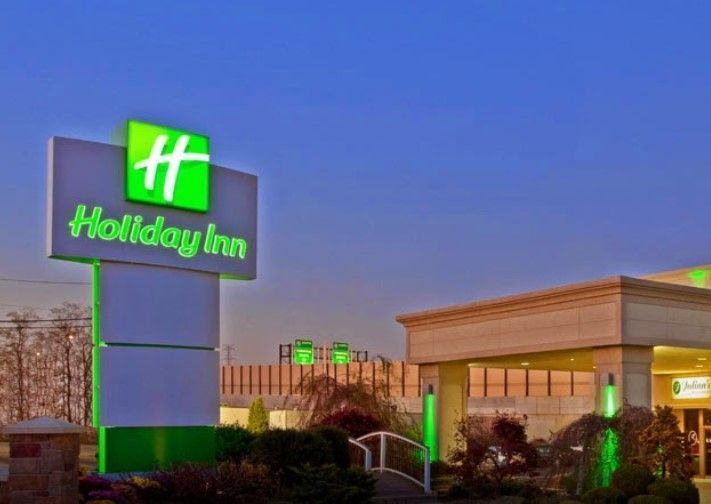 A hotel with a sign that says `` holiday inn '' is lit up at night.