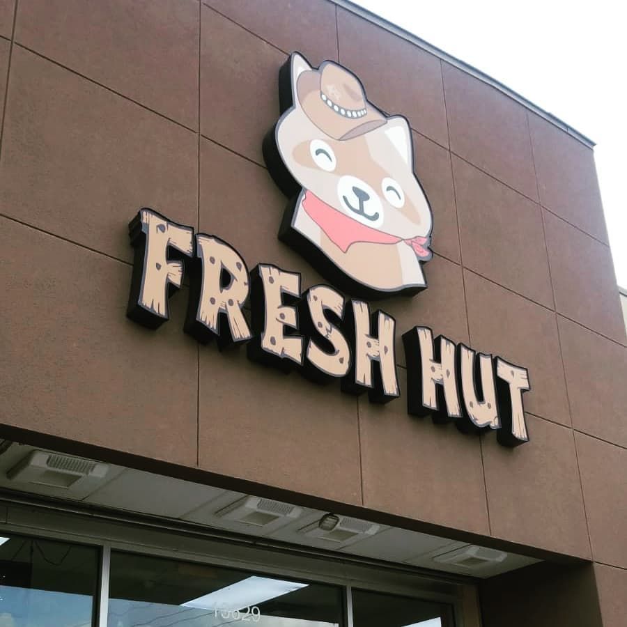 A fresh hut sign with a dog wearing a cowboy hat