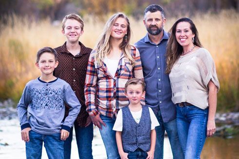 A family is posing for a picture in front of a river.