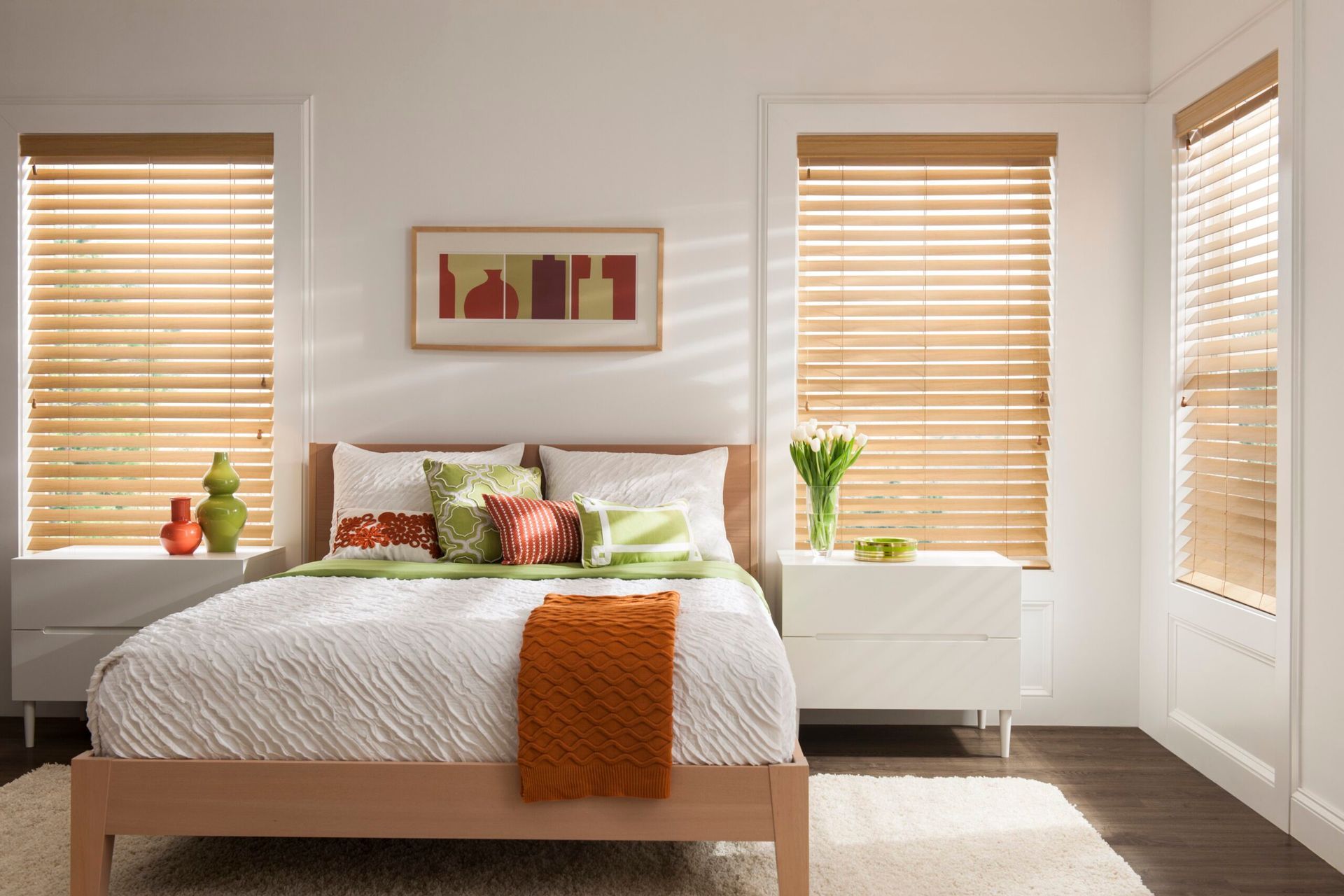 A bedroom with a bed and wooden blinds on the windows
